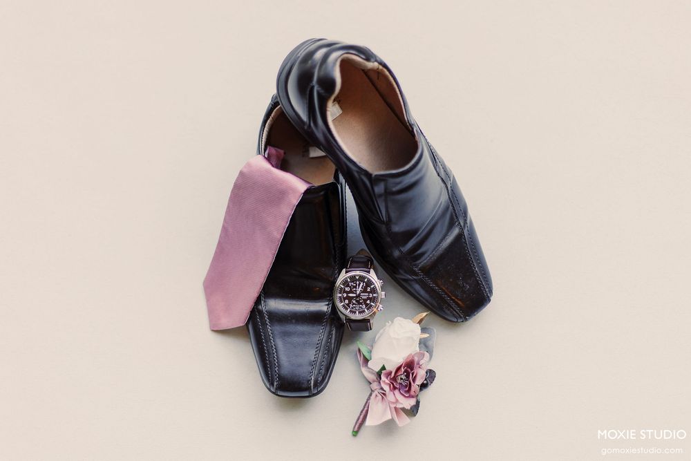 Pair of navy blue and pink baby shoes with decorative bows arranged in a minimalist style on white background.