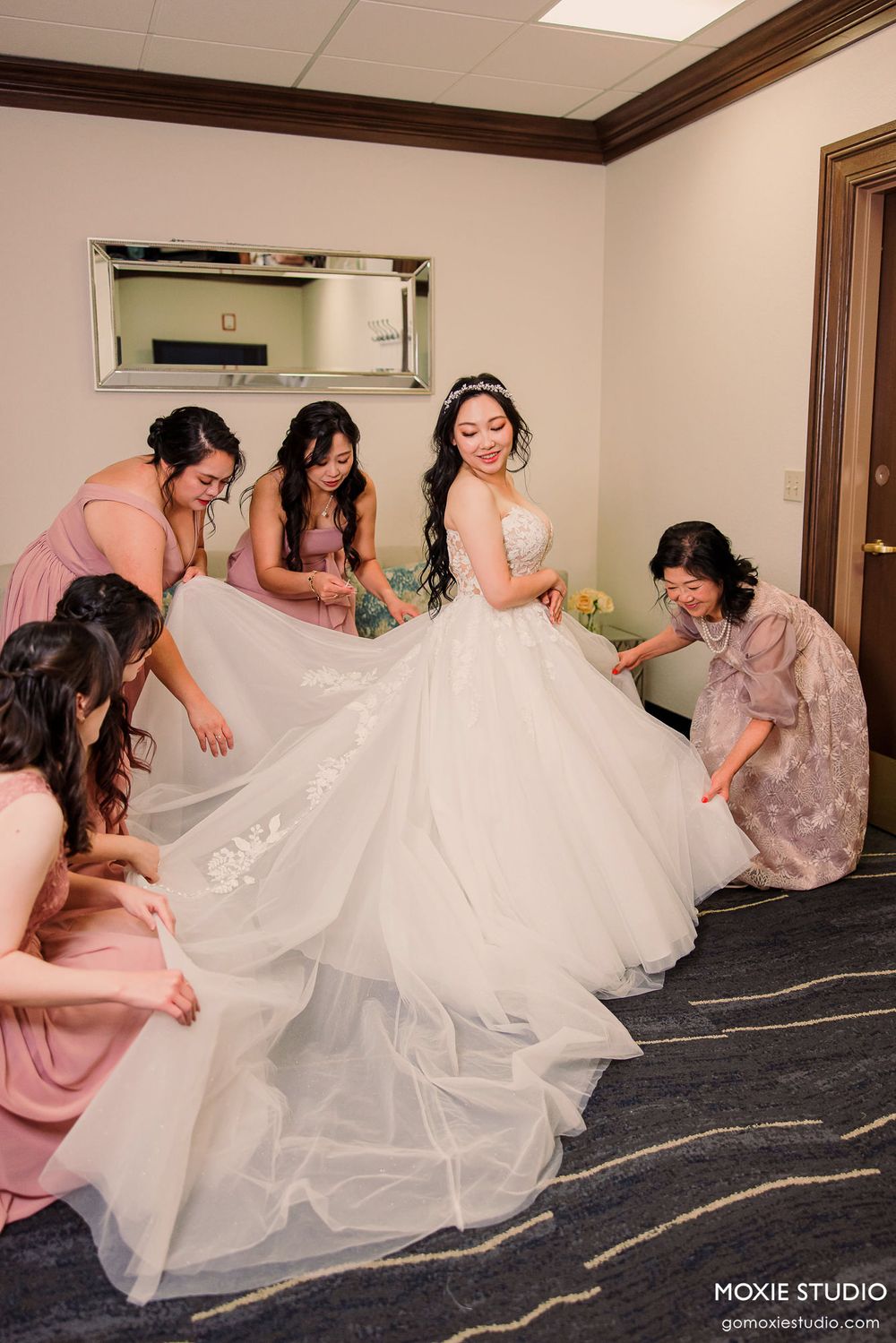 Wedding party helps adjust the layers of a flowing white wedding dress in a series of candid preparation moments.