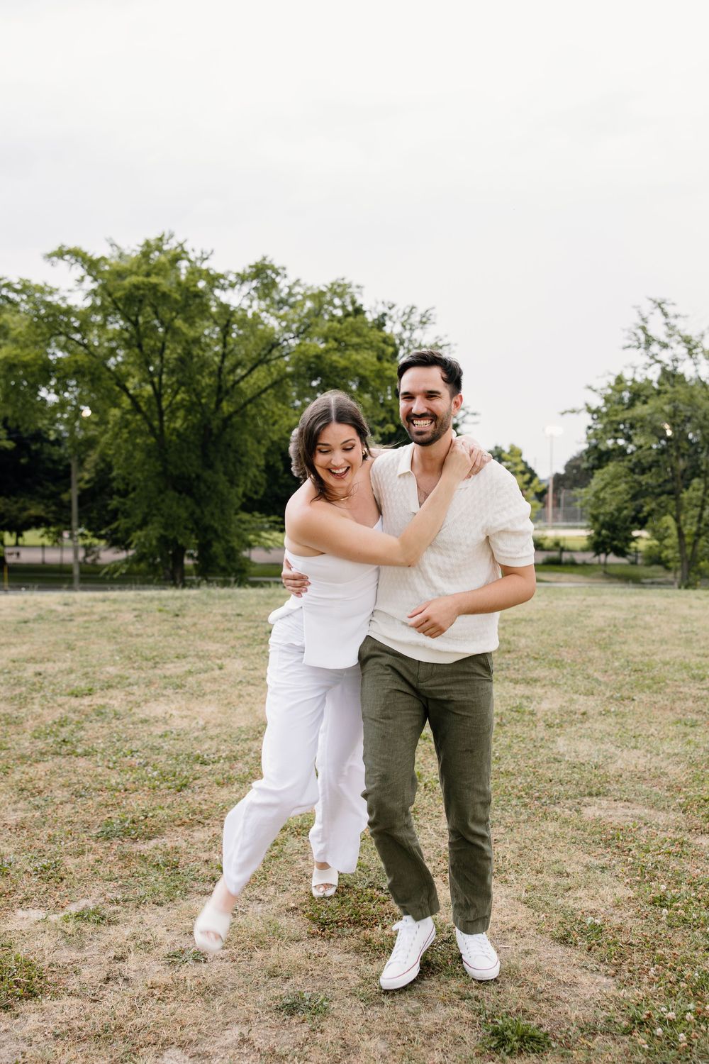 A playful moment captured outdoors with two people in white outfits against a grassy landscape.