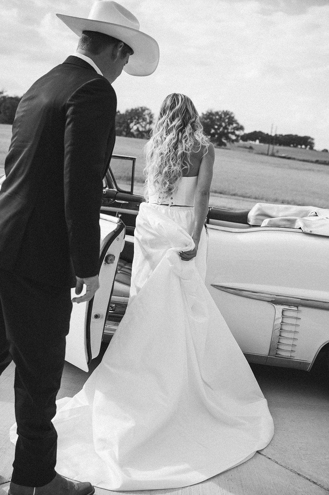 Black and white photo series shows couple in wedding attire getting into vintage car, with bride's white dress flowing.