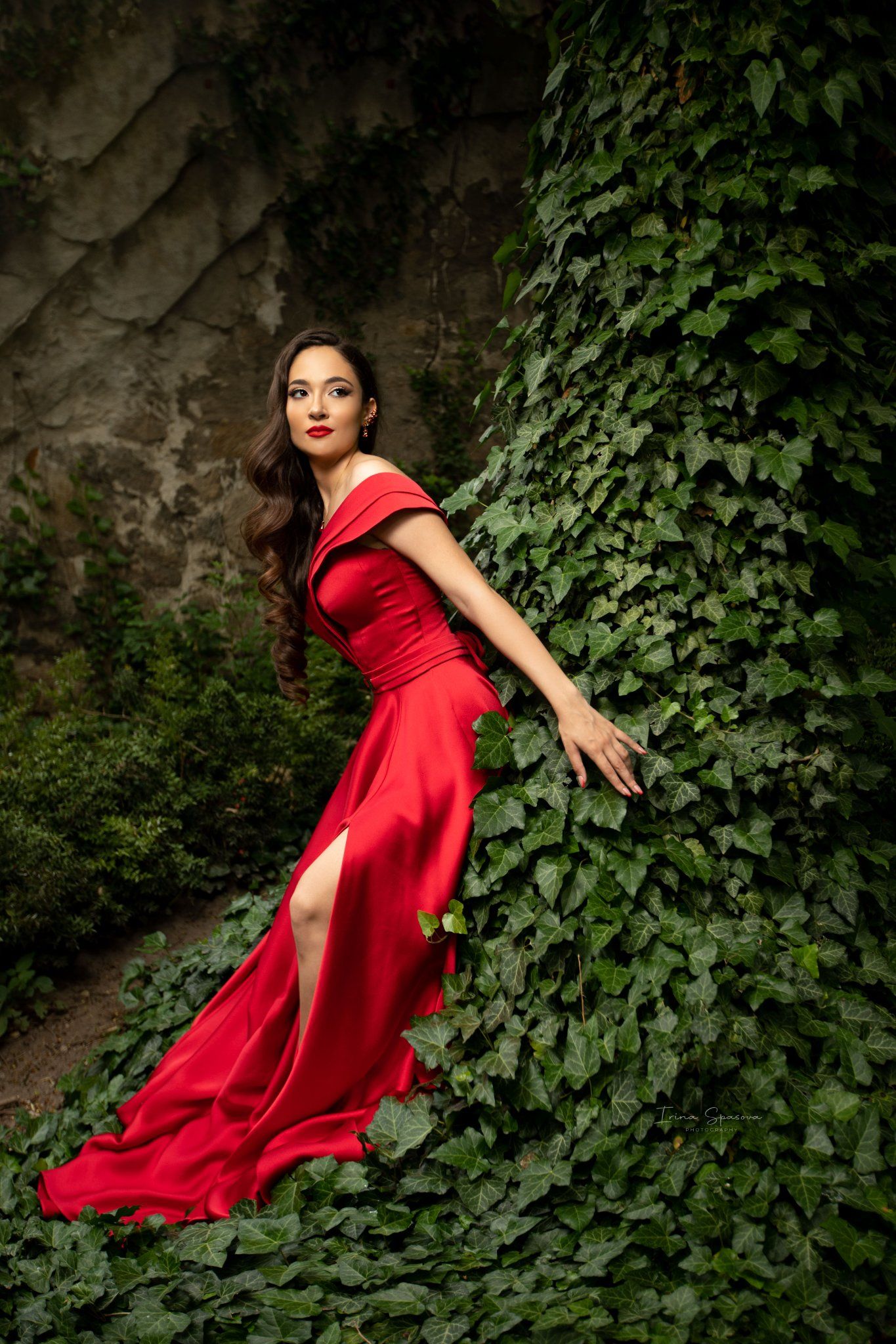 A flowing red dress twirls dramatically against a backdrop of green foliage.