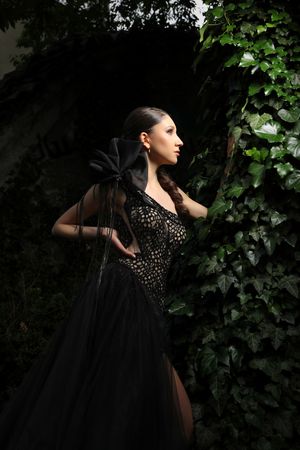 Dramatic black evening gown portrait against ivy-covered wall.