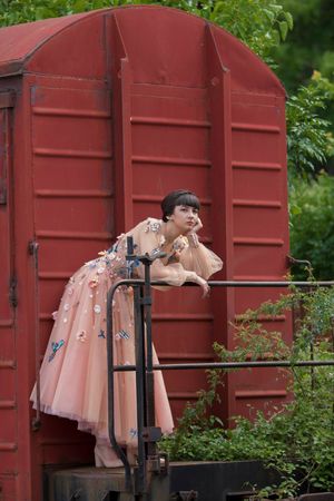 Pink vintage dresses displayed on clothing rack against red container wall.