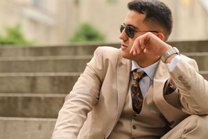 Multiple shots of a person in a light colored suit posing confidently with sunglasses.