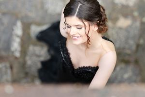 Soft focus portrait in black lace dress against stone wall.