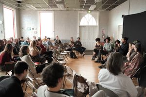 Large audience seated in a bright room during a presentation or workshop.