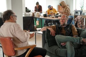 Two people having an animated discussion while sitting in a modern office lounge area.