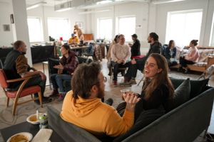 Group discussion in modern office space with people seated on couches.