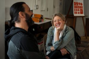 Two people having an animated conversation in an art studio or workshop setting.