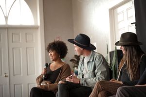 Panel discussion with three speakers sitting on chairs in a bright room with white walls and doors.