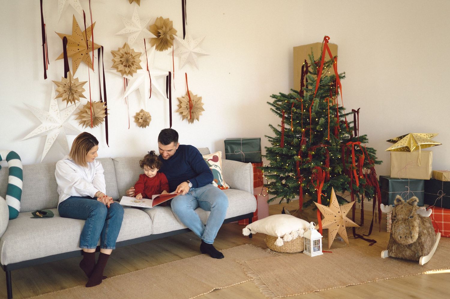 People gather around a decorated Christmas tree as holiday preparations and gift wrapping unfold in a living room.
