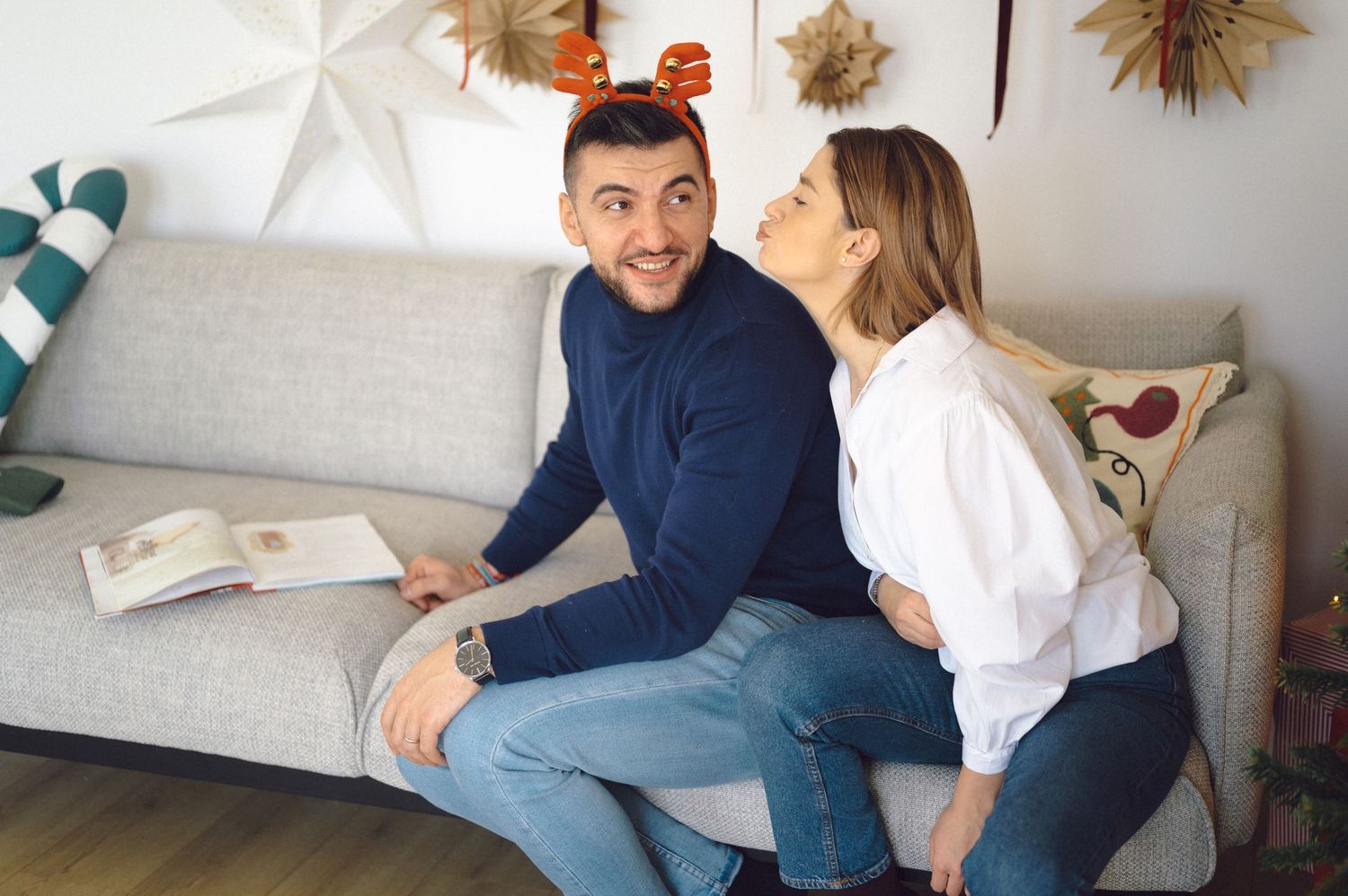 A series of lighthearted candid moments between a couple laughing and interacting on a couch in a bright living room.