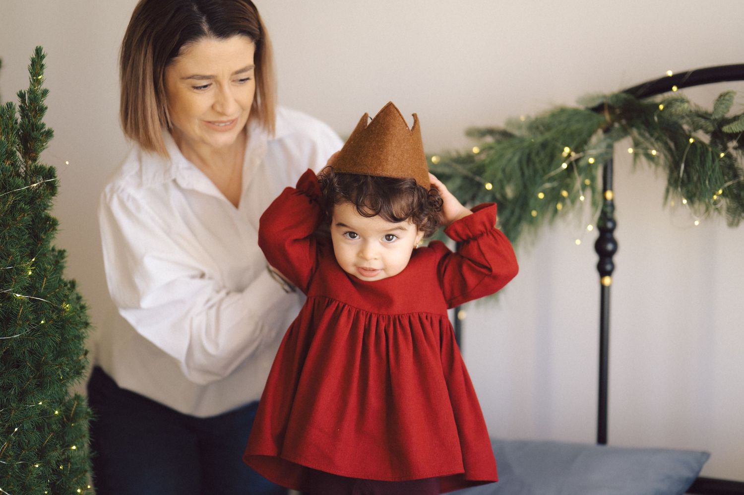 A series of photos showing hands helping a small child wearing a red dress with holiday decorations in the background.