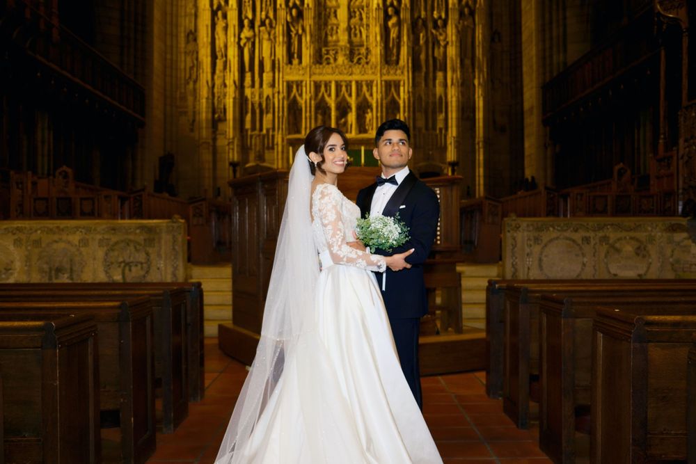Newlyweds share intimate moments in a dramatically lit cathedral with ornate gothic details.