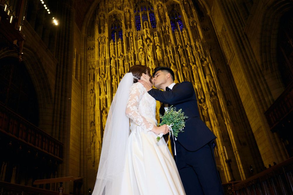 A couple celebrates their wedding in a majestic cathedral with golden architectural details.