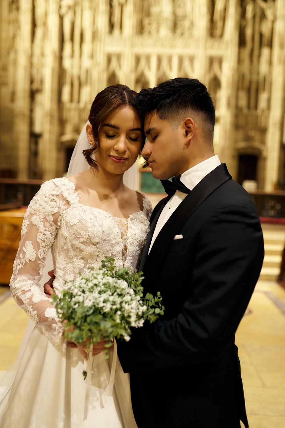 Intimate moment captured between newlyweds in cathedral with ornate golden backdrop.