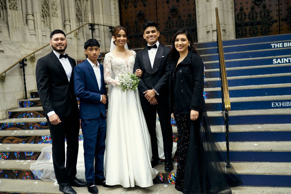 Wedding party of five poses on cathedral steps in formal attire.