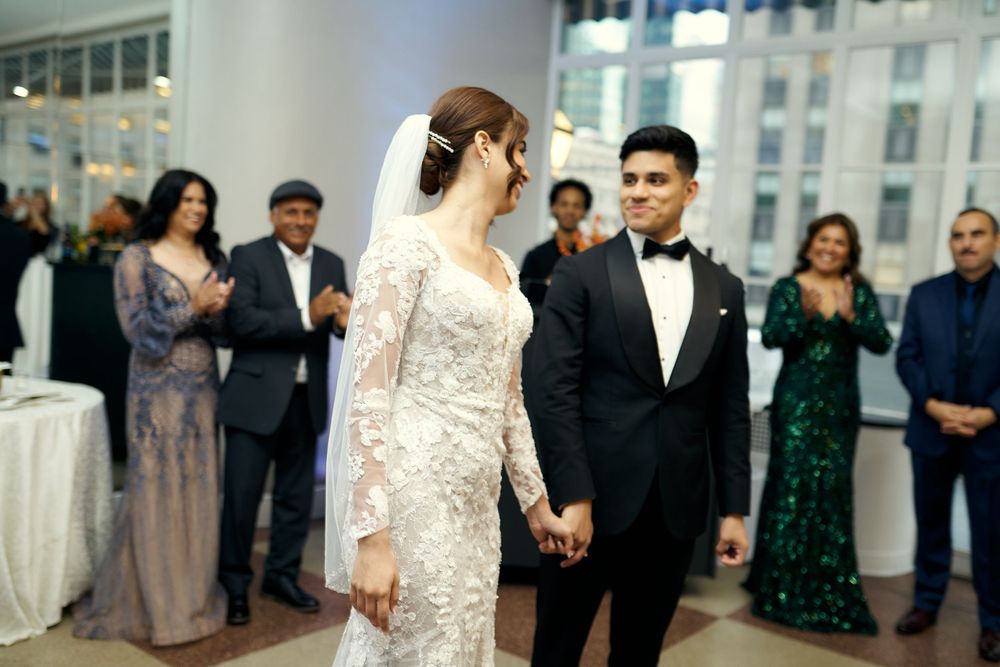 A wedding celebration in an elegant venue with guests watching the couple in formal attire at 3 west Club