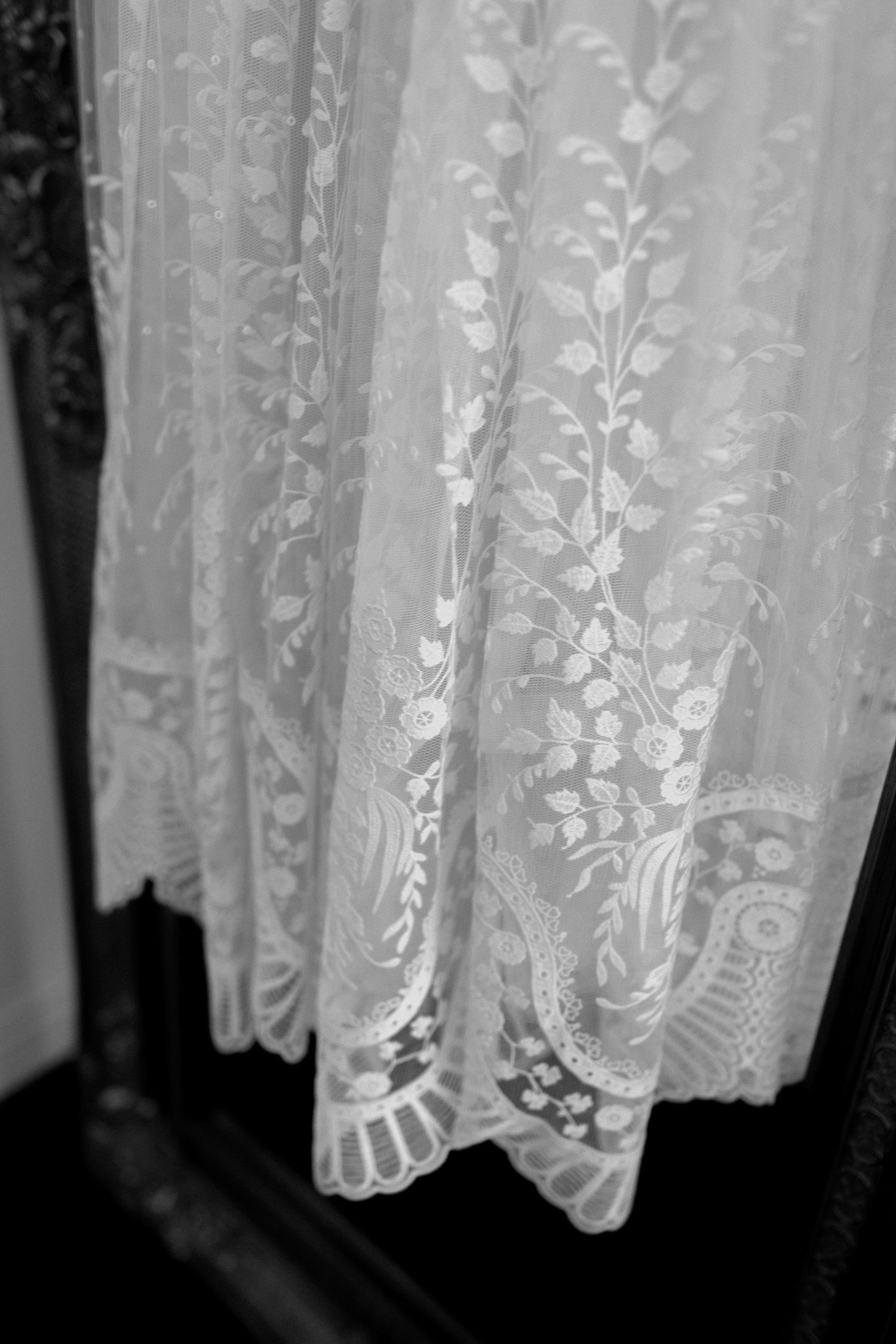 Close-up detail of delicate white lace fabric with floral and vine pattern embroidery in vintage style.