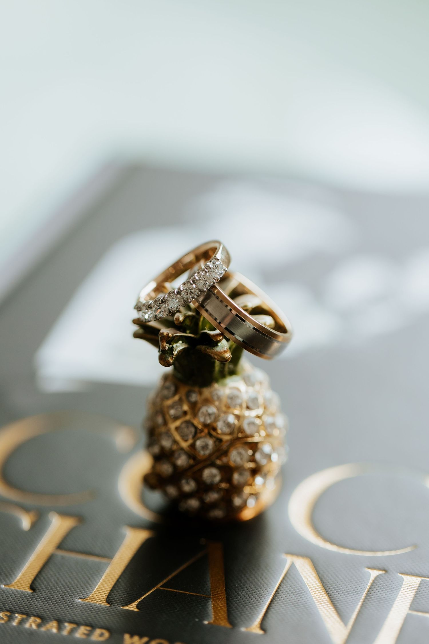 Diamond wedding rings stacked elegantly on a black and gold printed surface with shallow depth of field.