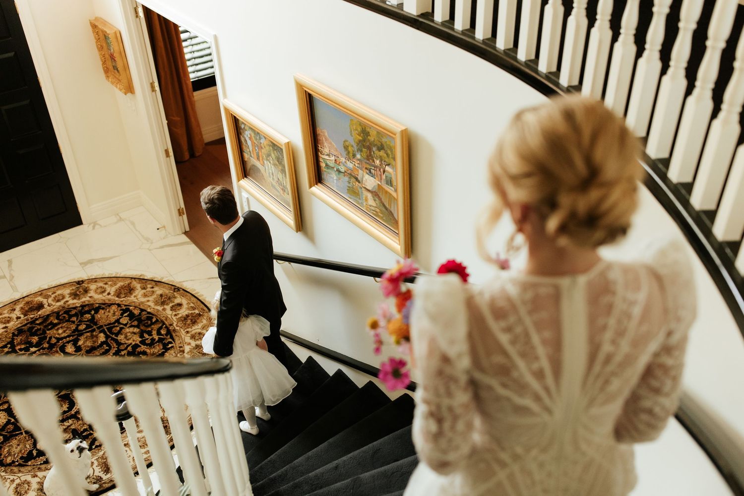 Elegant lace back detail of a white wedding dress captured against a traditional wooden staircase.