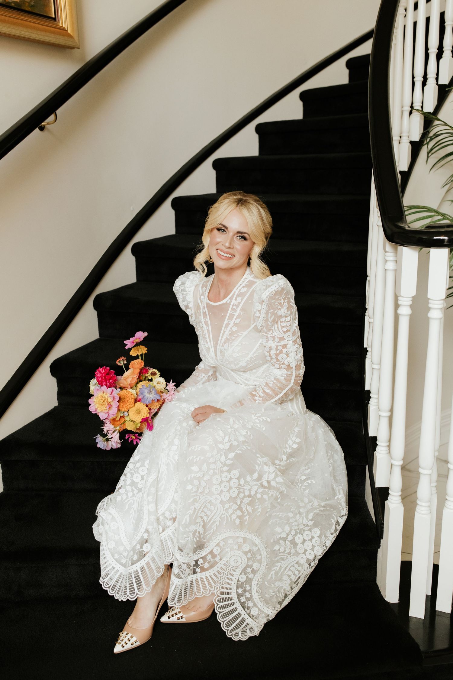 Beautiful lace wedding dress and colorful bouquet showcased on an elegant curved staircase.