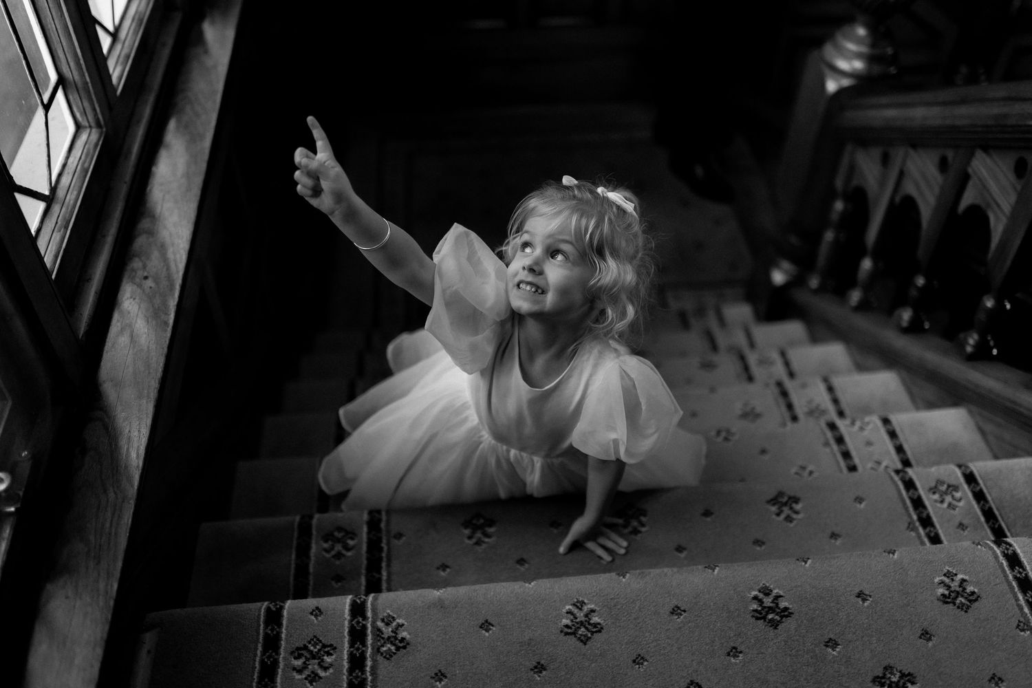 Black and white photo of playful moment on vintage carpeted stairs.