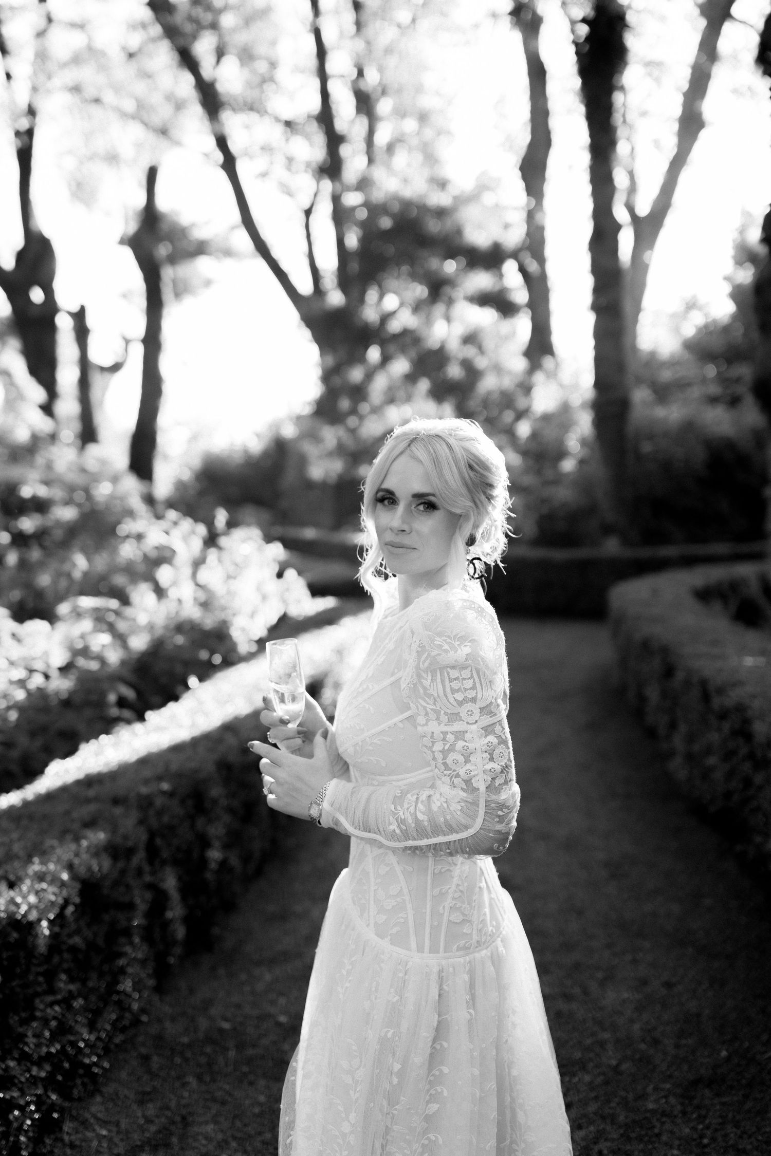 A series of dreamy black and white photos showing a figure in a vintage white lace dress outdoors among trees.