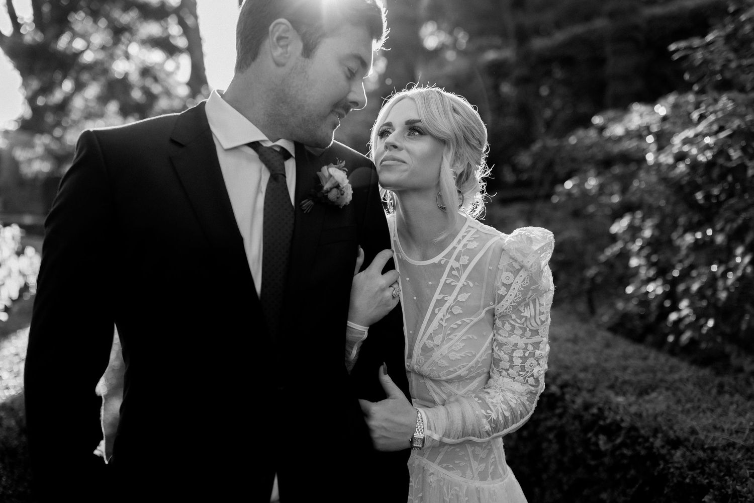 A series of black and white romantic wedding photos capturing intimate moments in an outdoor garden setting.