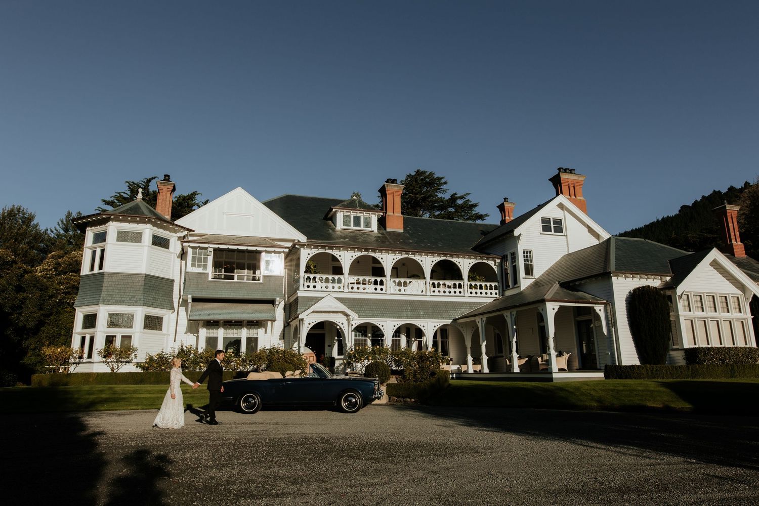 Multiple luxurious white beach houses with arched windows and large patios line a scenic waterfront property.