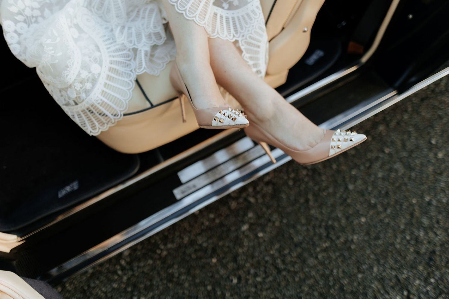 A close-up of sparkling rhinestone bridal shoes as someone steps into a classic car.