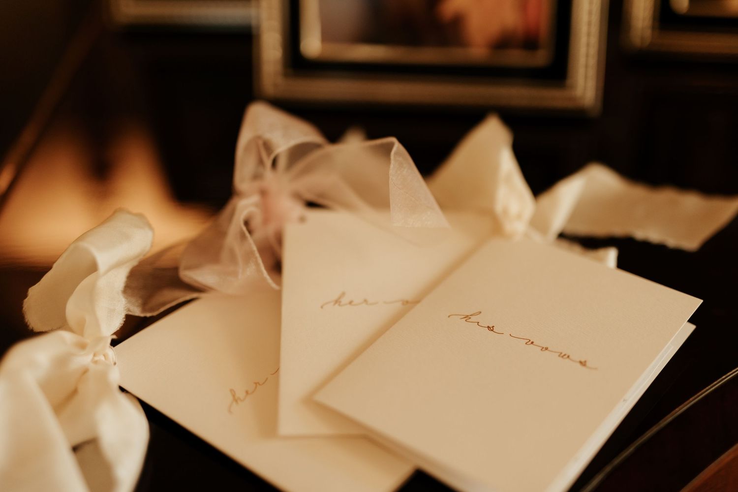 Elegant wedding invitation cards with delicate calligraphy laid out on a dark surface with soft lighting.