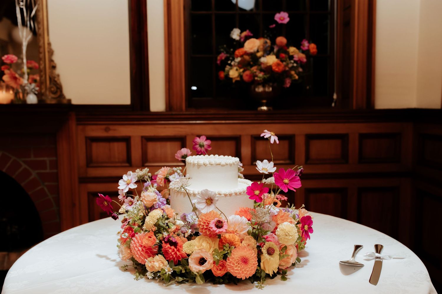 Wedding reception table decorated with elegant pink and peach floral centerpieces and glowing candles.