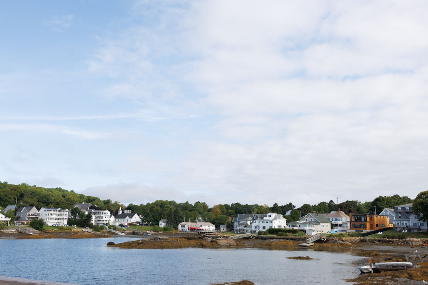 Coastal New England village with waterfront homes and boats along a scenic harbor.