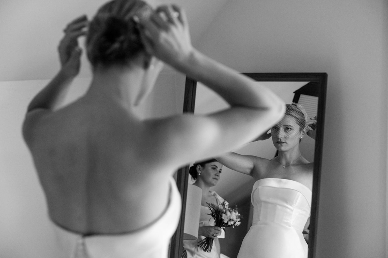 Black and white reflection of wedding preparation in mirror.