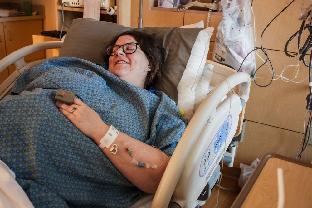 Patient resting in hospital bed with medical monitoring equipment.