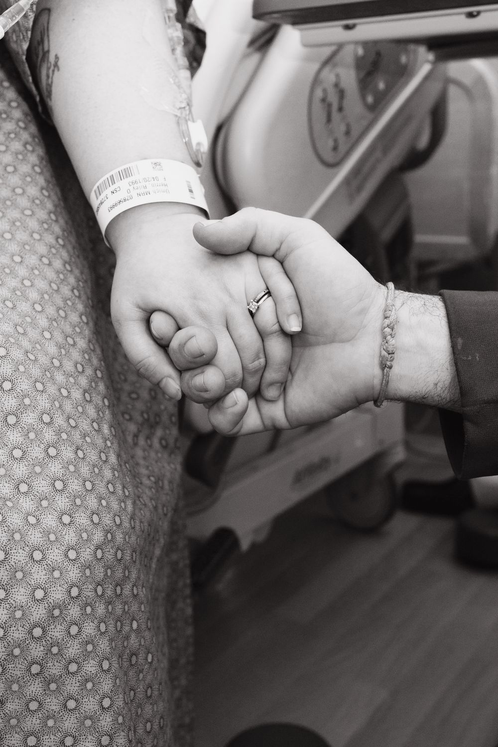 Black and white image of hands holding each other in an intimate moment.