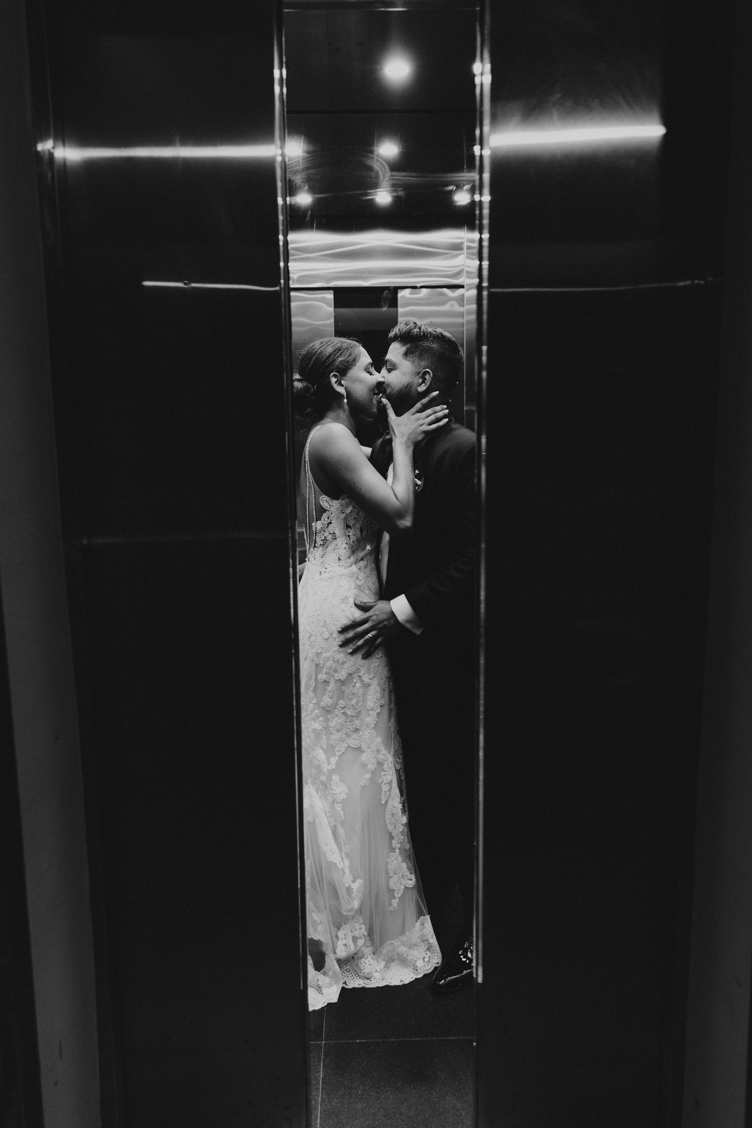 A dramatic black and white elevator photo captures an intimate wedding moment.