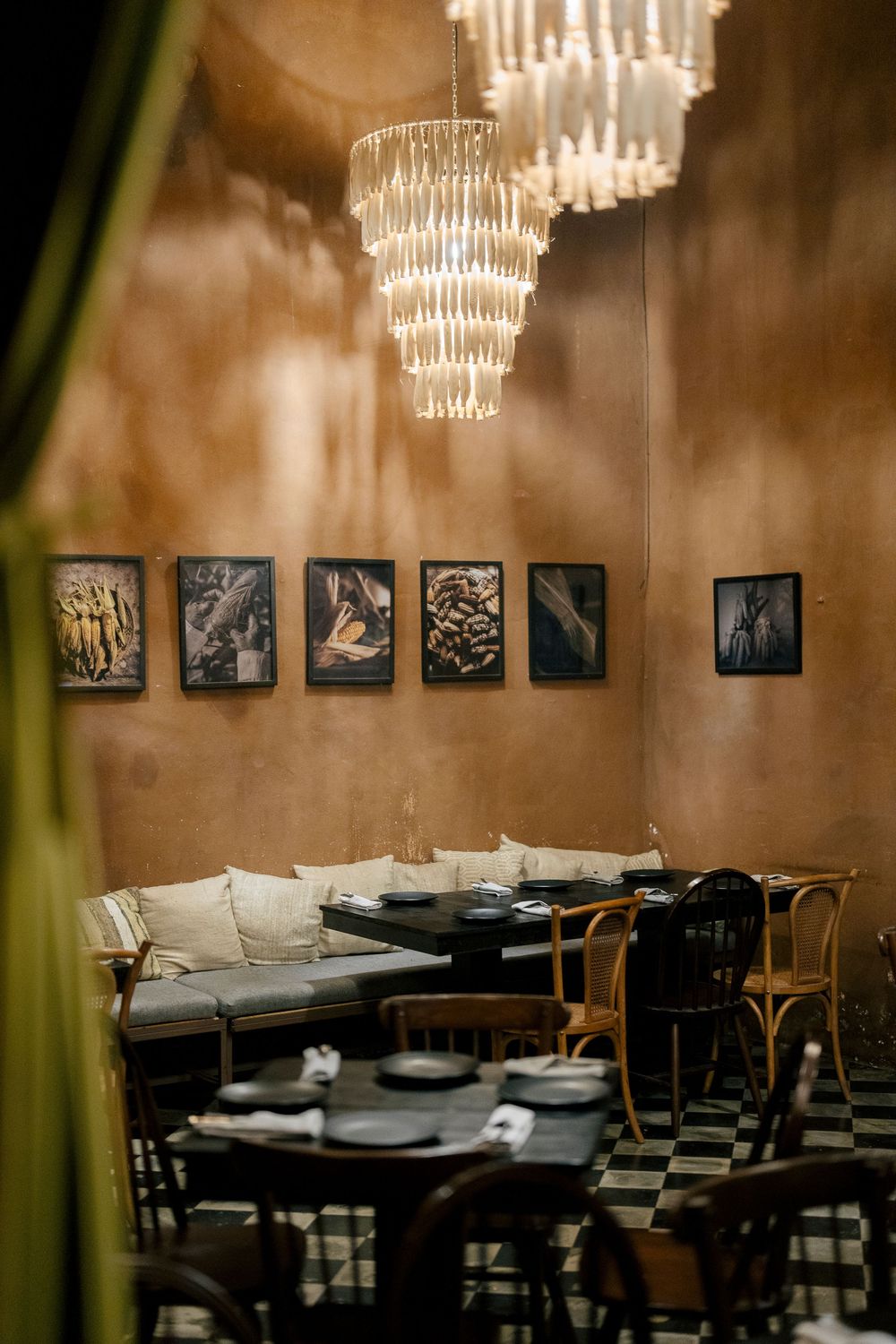 Elegant restaurant interior features crystal chandelier, black-framed artwork, and plush white seating against warm walls.