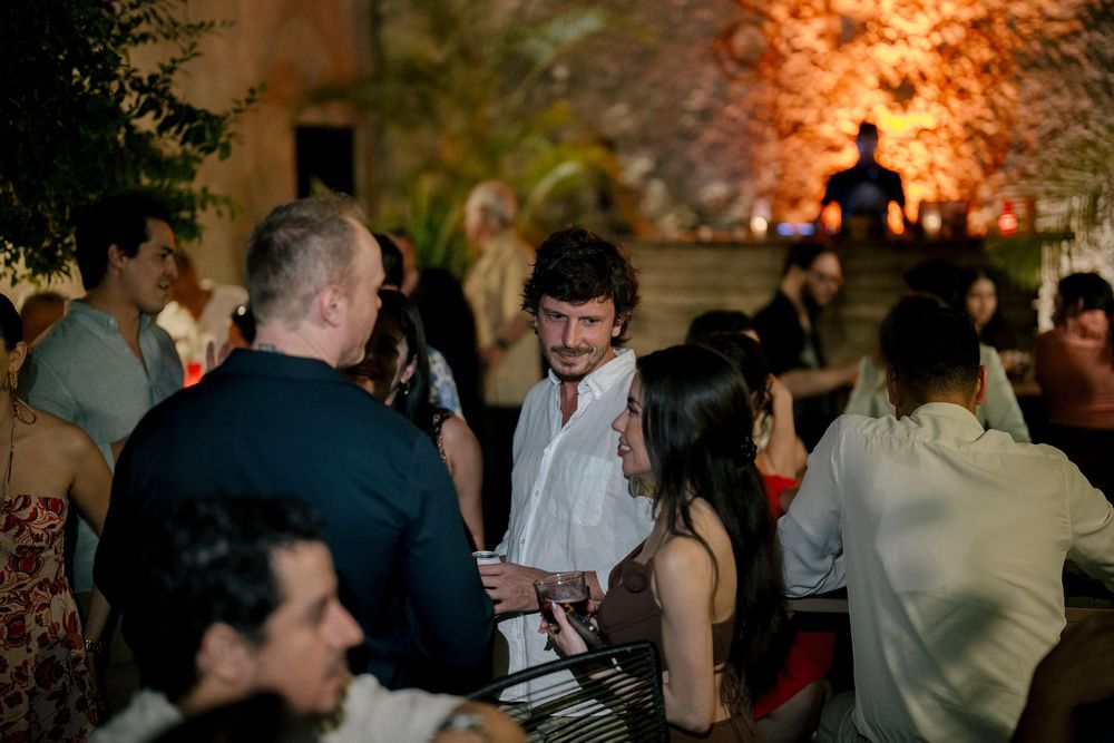 People gathered at an evening social event with warm lighting and stone walls in the background.