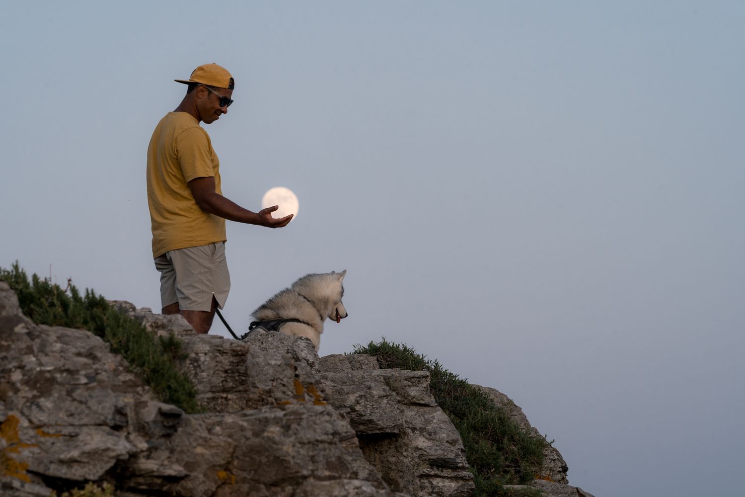 un homme tient dans sa main la lune qui est pleine