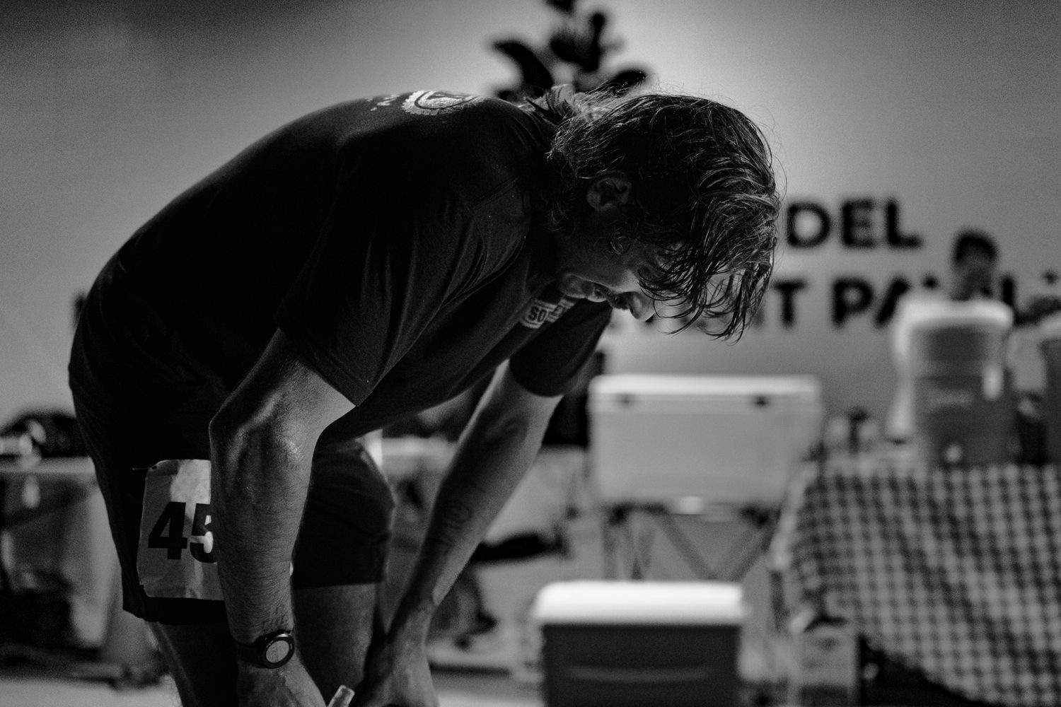 A performer leans forward on stage during a performance, captured in dramatic black and white.
