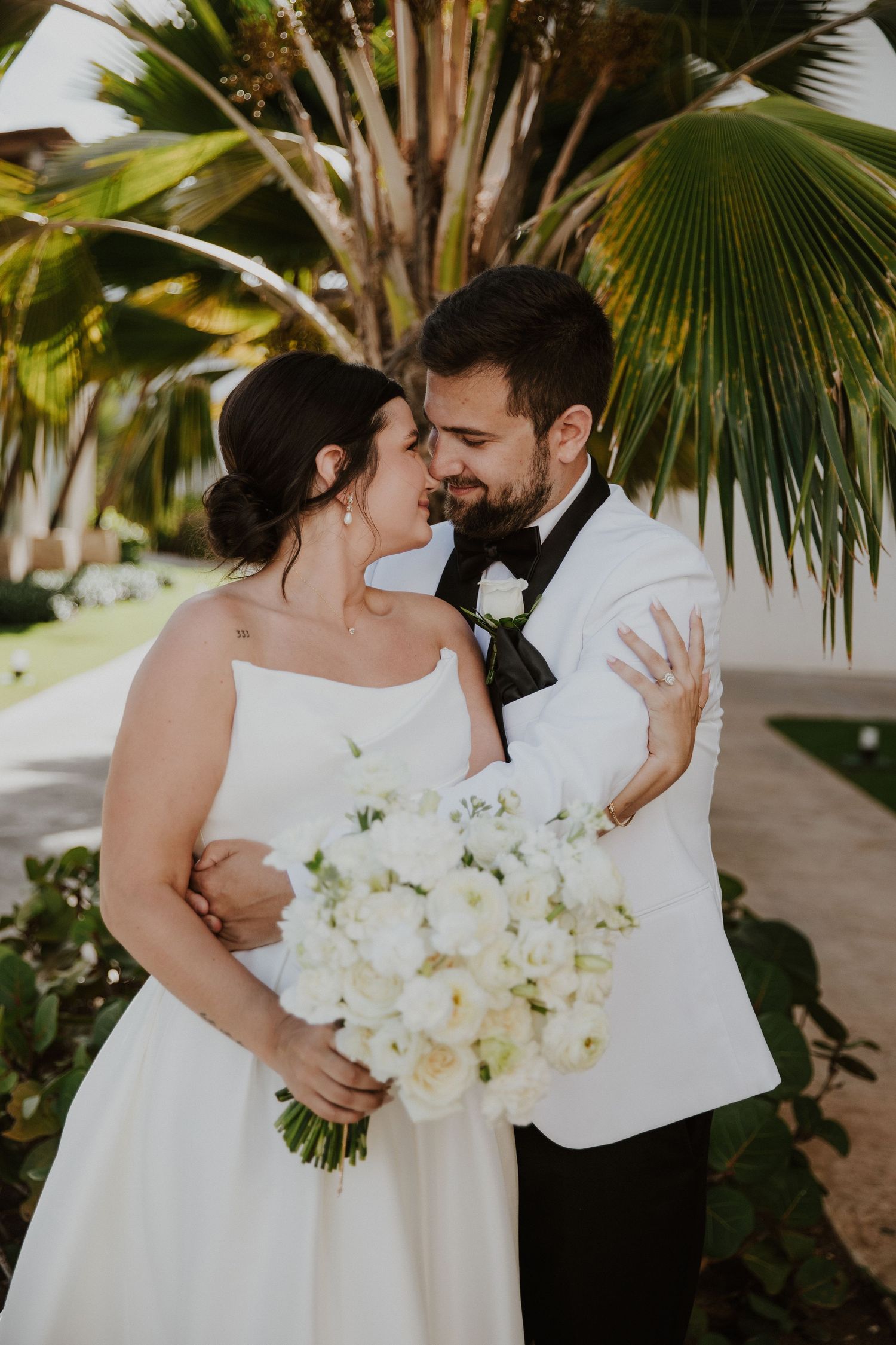 A tropical wedding ceremony with palm trees and white floral bouquet.