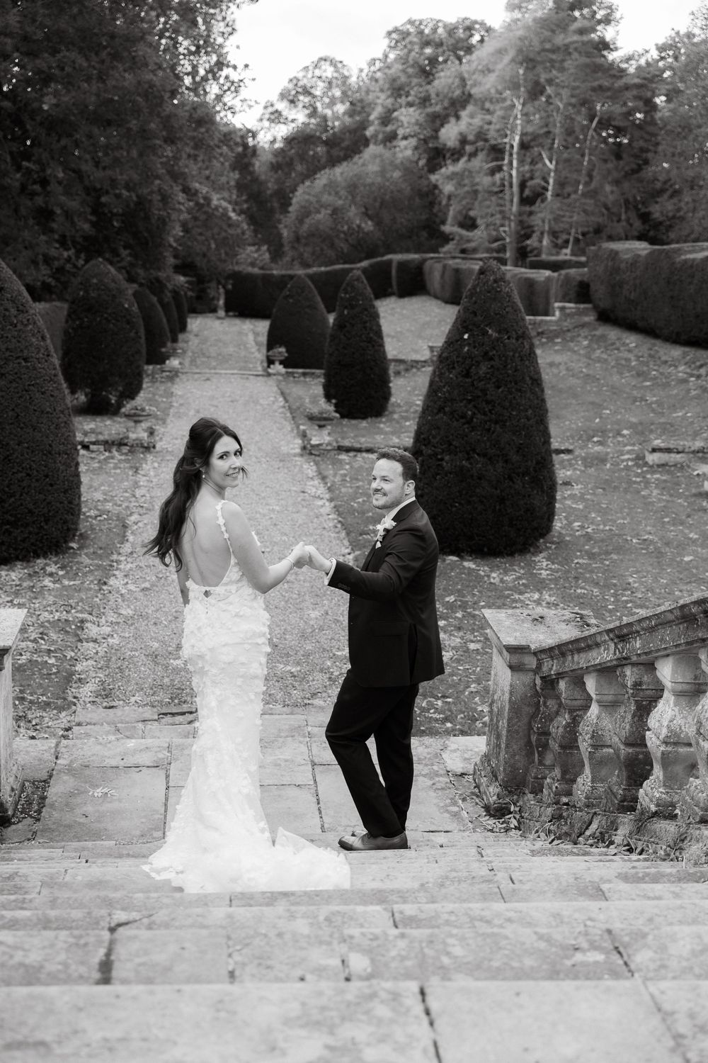 Black and white photo series of couple ascending stone garden steps during wedding shoot.
