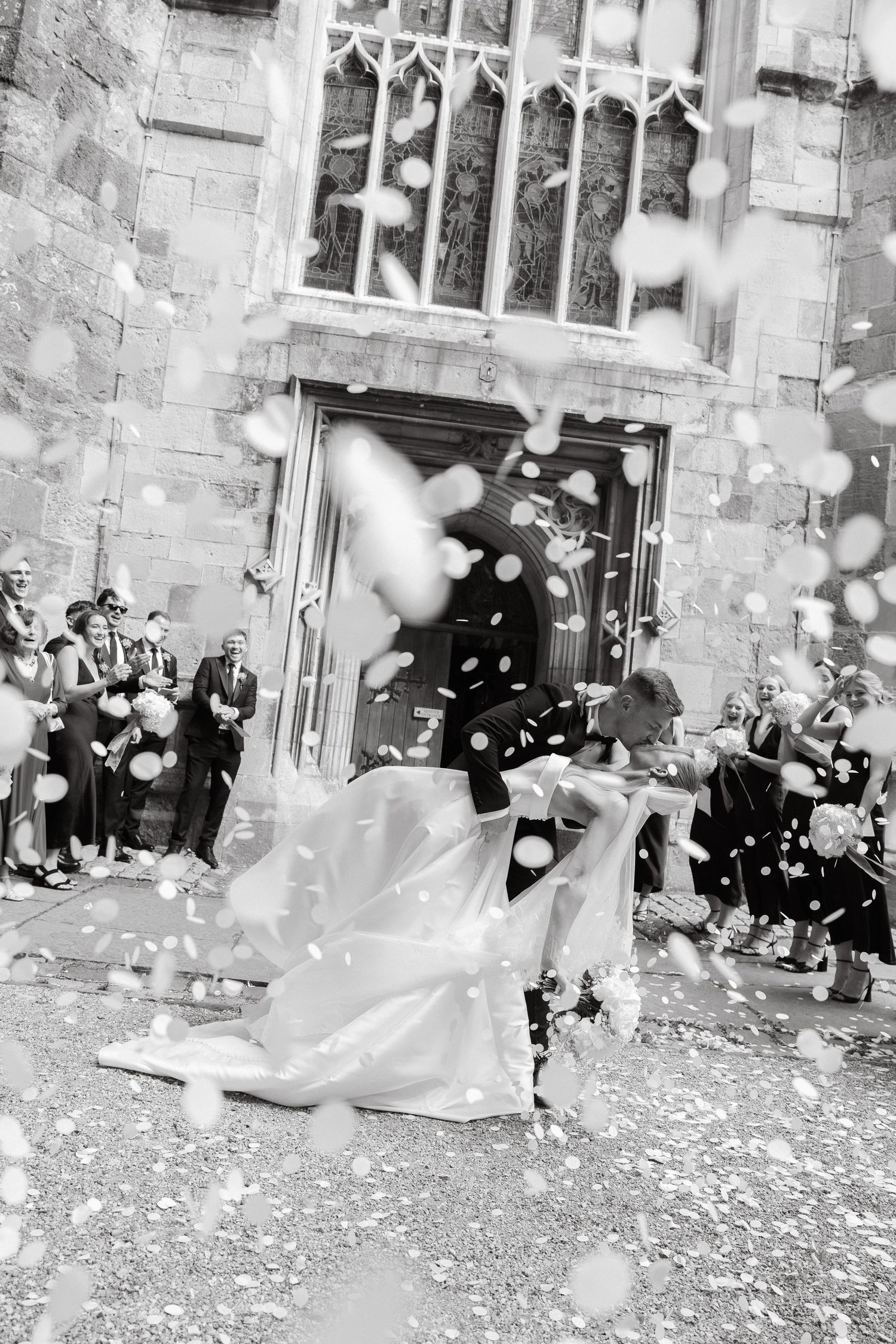 Wedding exit celebration with confetti being thrown outside a stone church building.
