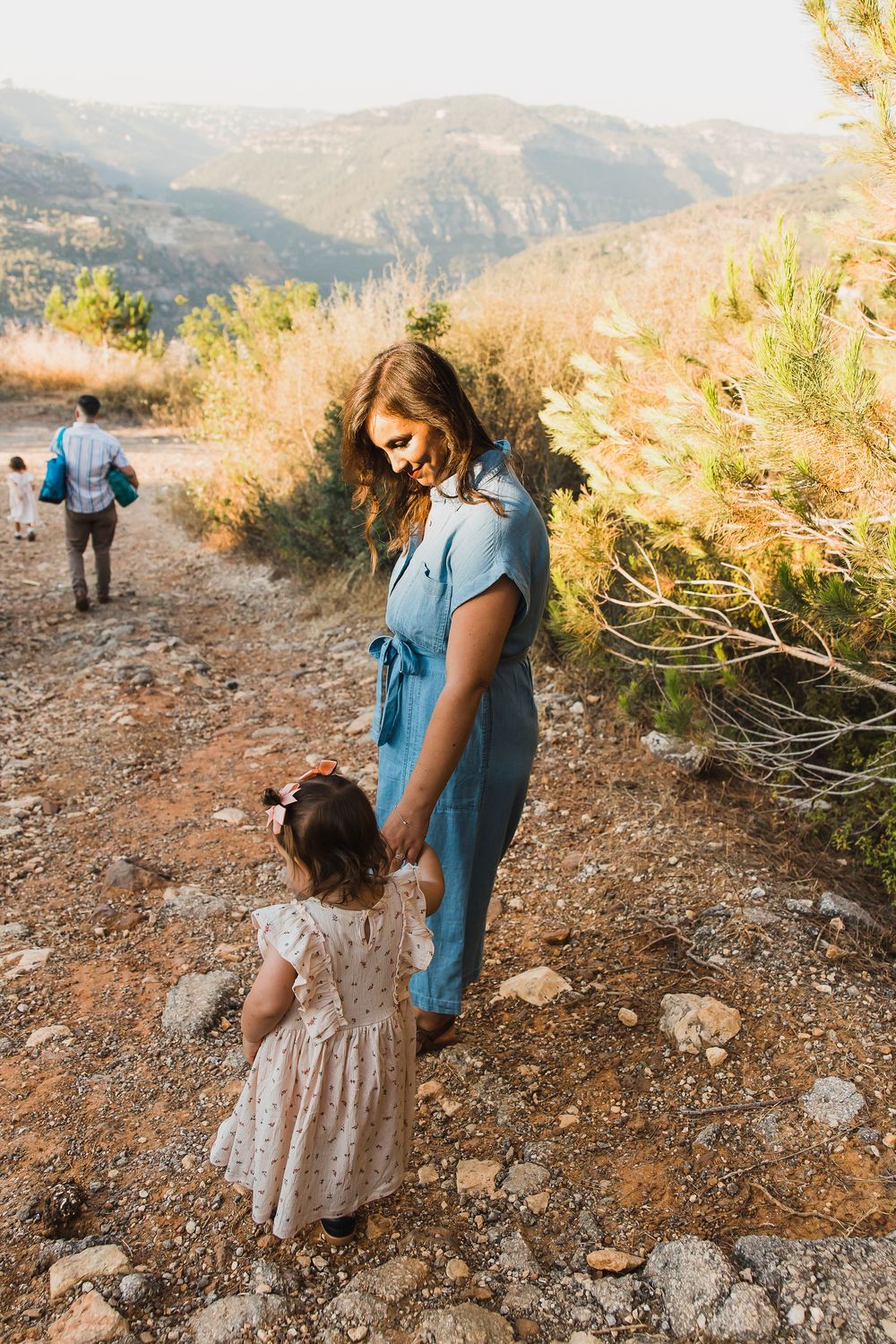 Family exploring a scenic mountain trail together on a warm autumn day with golden light and natural terrain.
