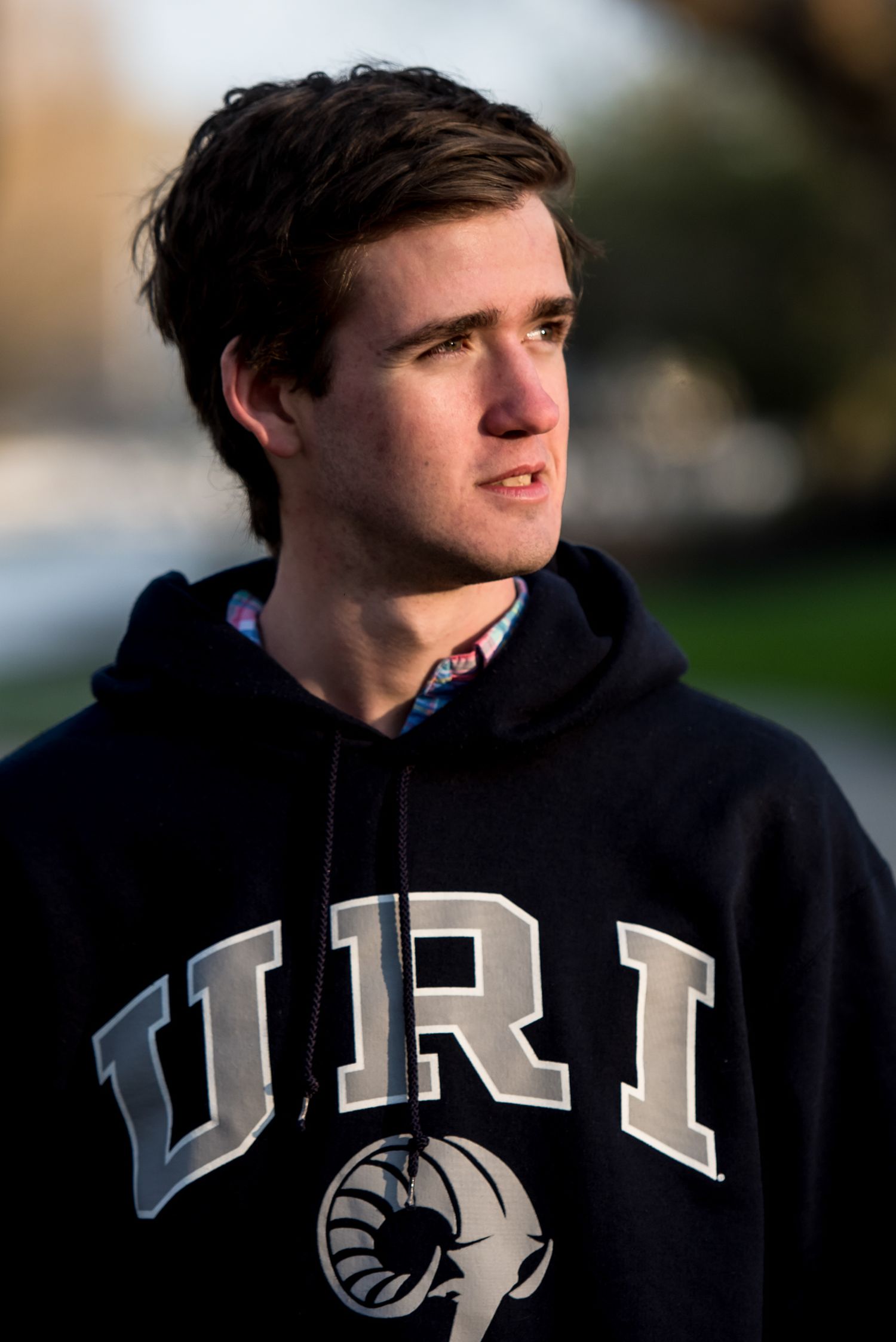 Side profile views of someone wearing a dark PITT hoodie with white lettering against a blurred background.