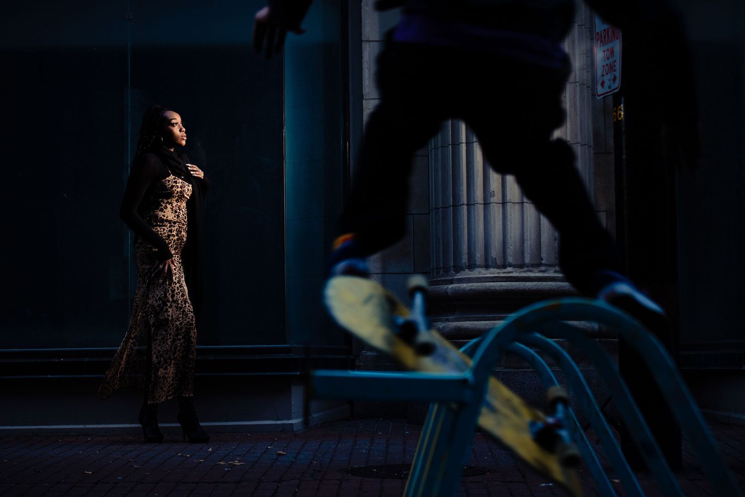 Silhouetted figure walking past illuminated storefront windows at night.