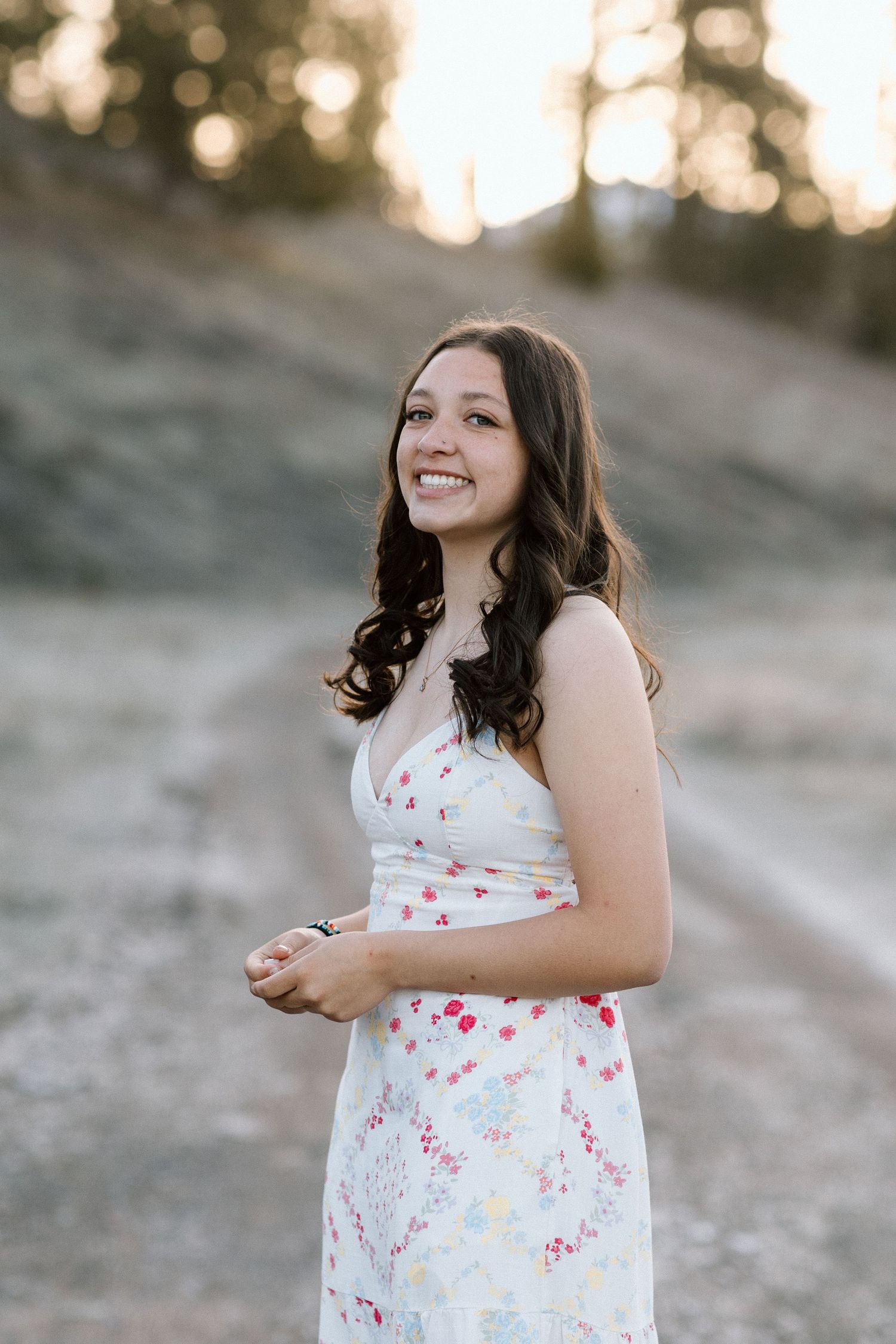 A white floral dress twirls gracefully against a sunlit mountain backdrop.