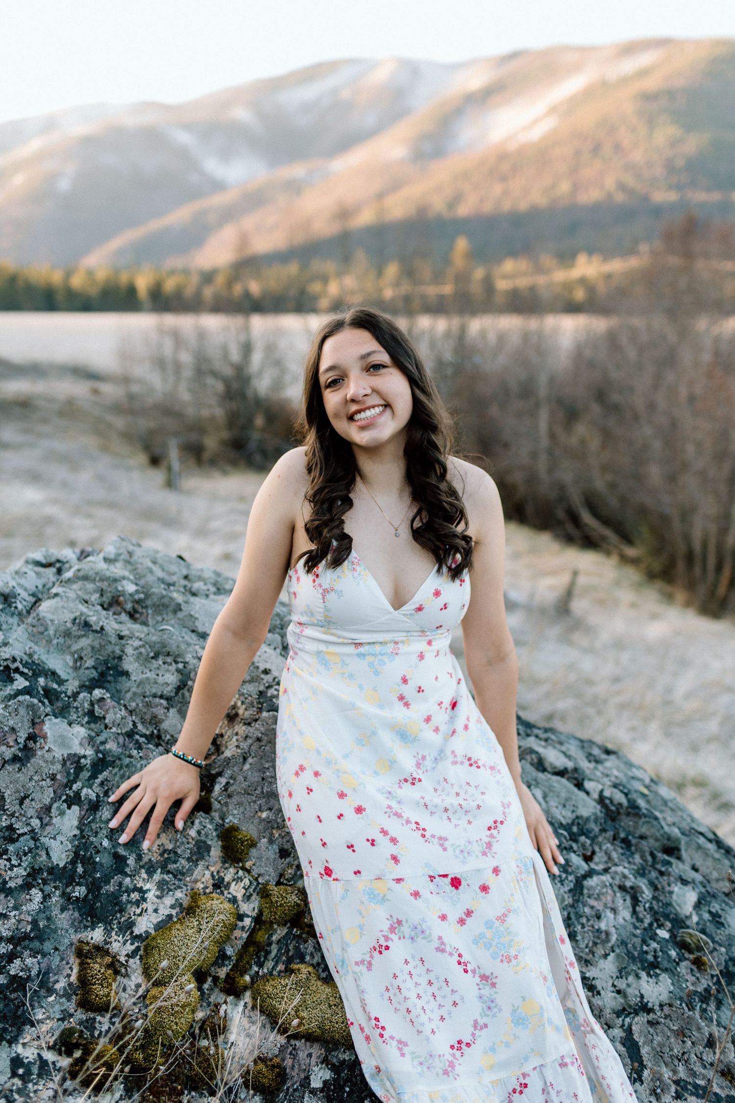White floral dress contrasts beautifully against rugged mountain rocks at sunset.